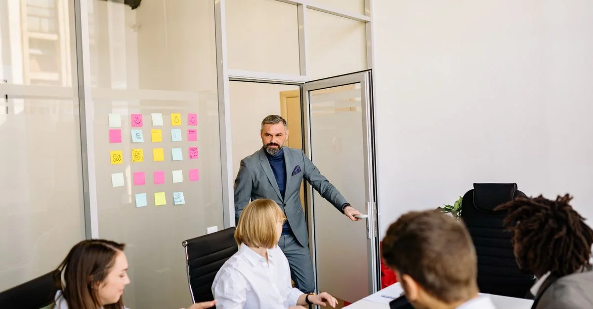 Équipe professionnelle collaborant dans une salle de conférence avec des post-it sur une porte en verre.
