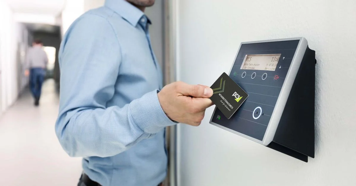 Un homme d'affaires utilise un lecteur de carte RFID pour un accès sécurisé au bureau, renforçant la sécurité au travail.