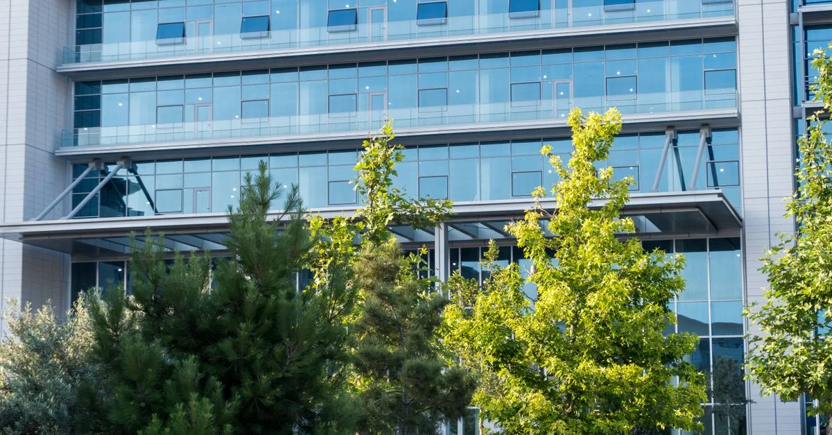 Extérieur d'un immeuble de bureaux en verre avec une végétation luxuriante, capturant le mélange de nature urbaine.