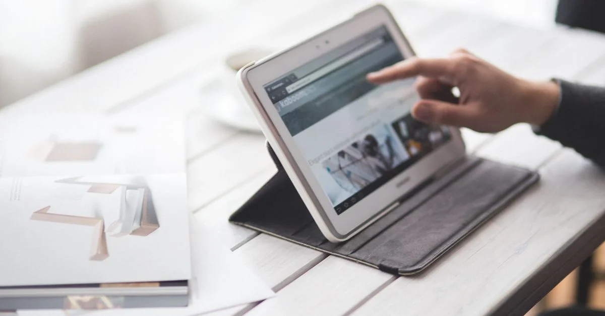 Une personne utilisant une tablette sur un bureau élégant, illustrant un cadre de travail contemporain.