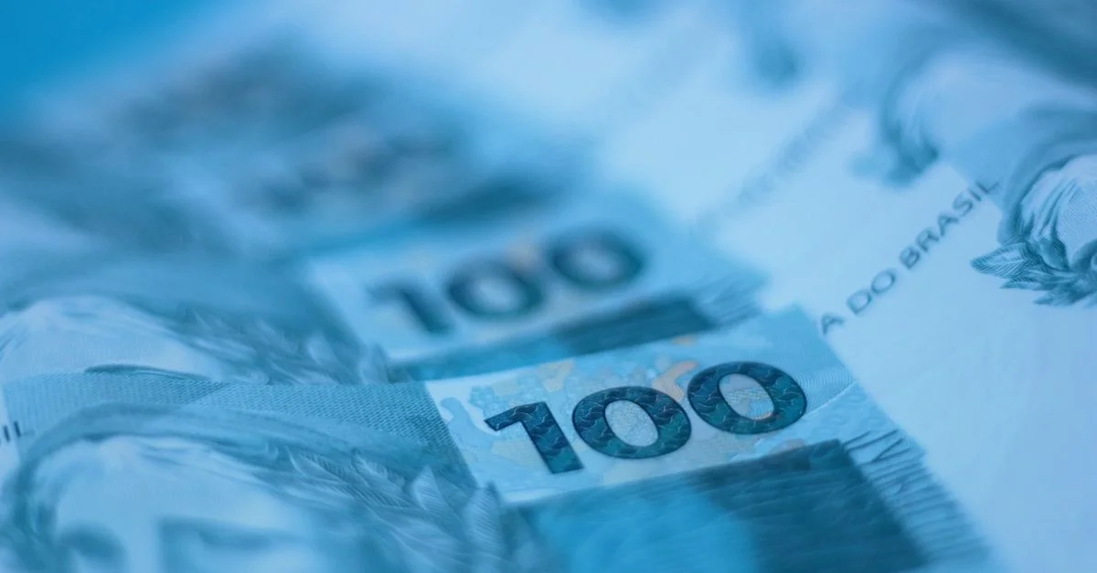 Vue en gros plan floue de billets de 100 réal brésiliens, mettant en valeur les détails de la monnaie.