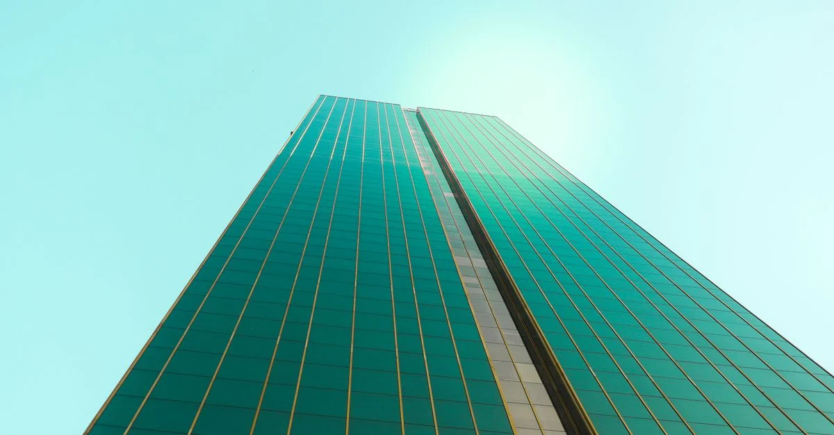 Un gratte-ciel imposant avec une façade en verre lisse contre un ciel bleu clair.
